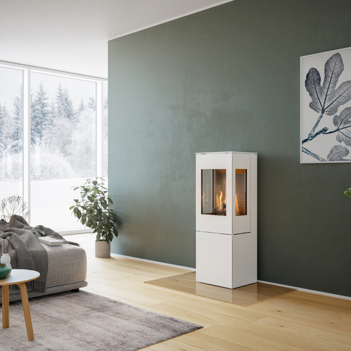 NEXO 120 GAS in bianco con porta in acciaio Stufa a gas NEXO 120 in bianco con porta in acciaio e due finestre laterali davanti a una parete verde in un soggiorno decorativo